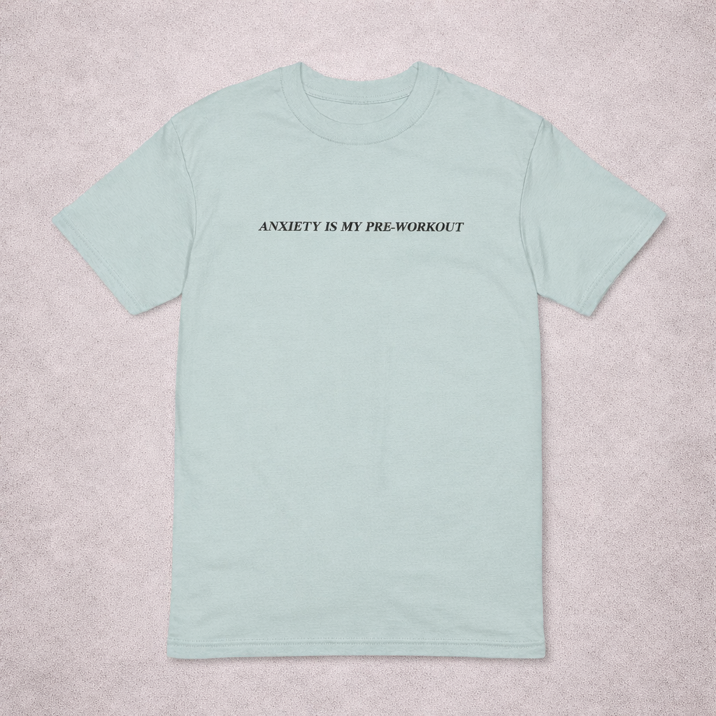 Light blue t-shirt with text 'ANXIETY IS MY PRE-WORKOUT' on a light gray background