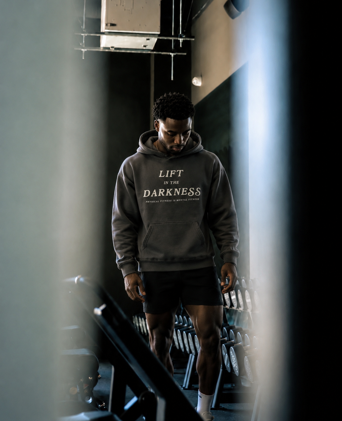 Man in the gym wearing a hoodie that says "lift in the darkness"