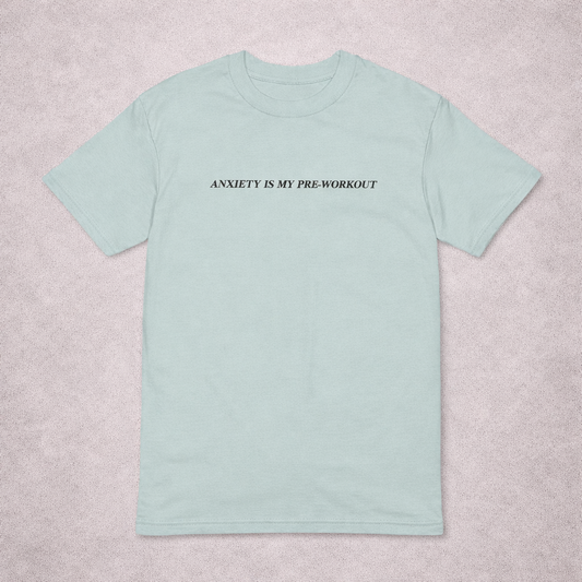 Light blue t-shirt with text 'ANXIETY IS MY PRE-WORKOUT' on a light gray background
