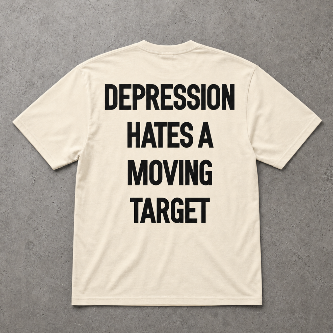 Beige t-shirt with motivational text on the back against a gray background