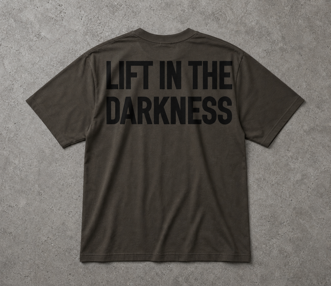 Dark gray t-shirt with 'LIFT IN THE DARKNESS' text on the back against a gray background