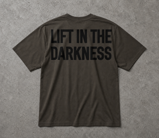 Dark gray t-shirt with 'LIFT IN THE DARKNESS' text on the back against a gray background
