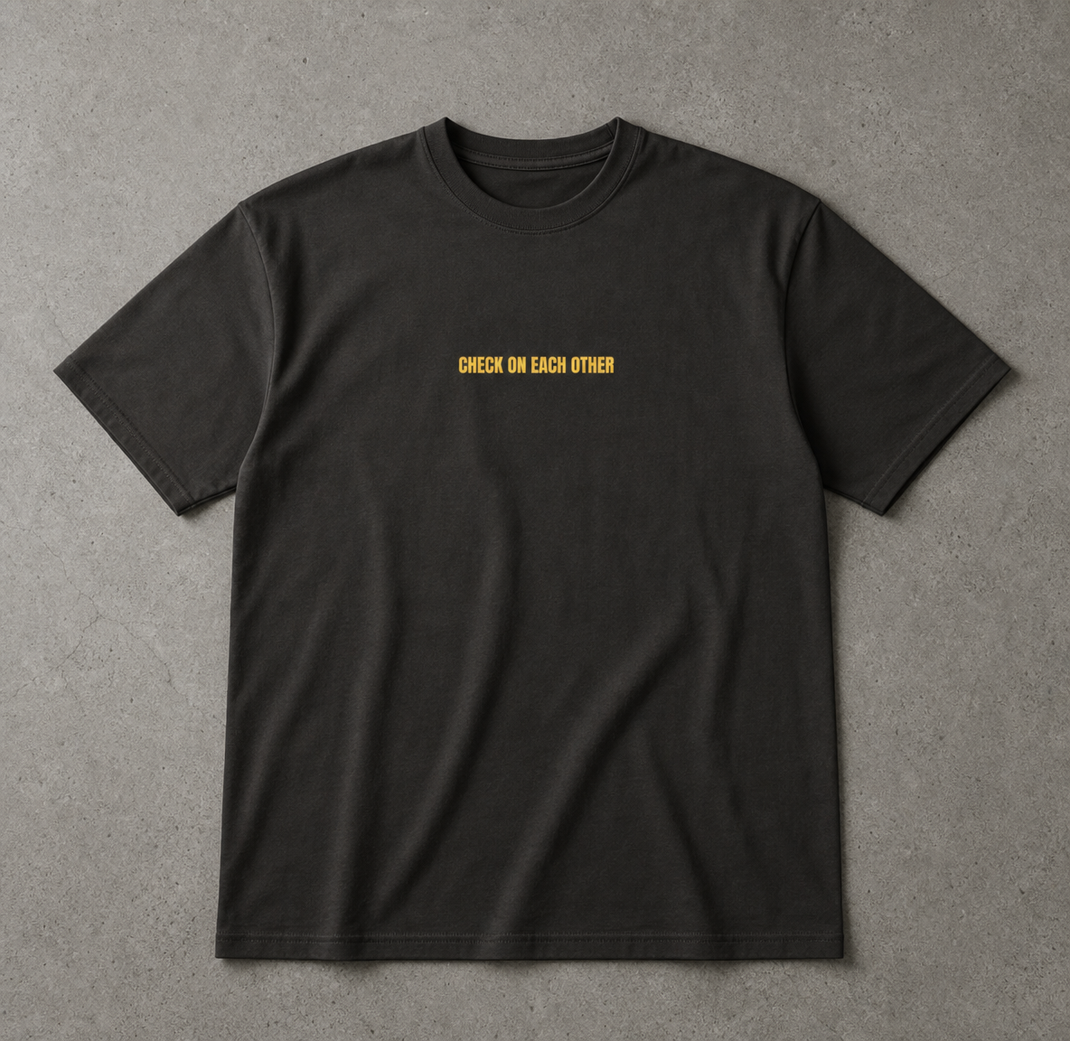Black t-shirt with yellow text 'CHECK ON EACH OTHER' on a gray background