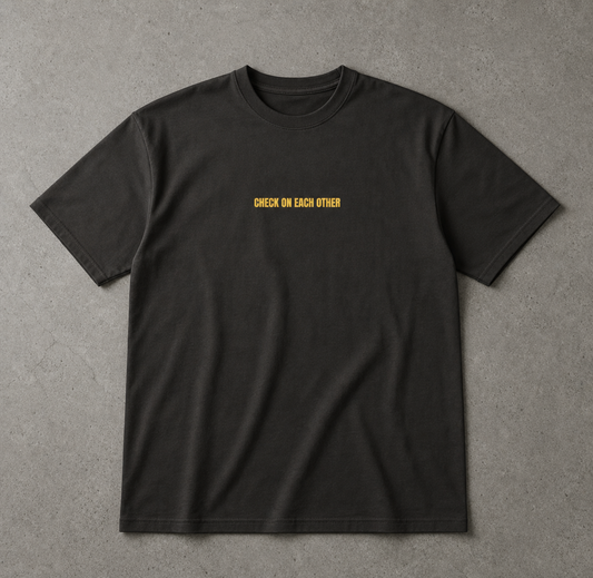 Black t-shirt with yellow text 'CHECK ON EACH OTHER' on a gray background