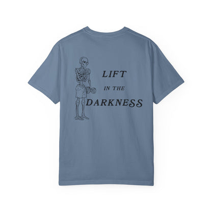 Blue t-shirt with skeleton graphic and text 'Lift in the Darkness' on a white background