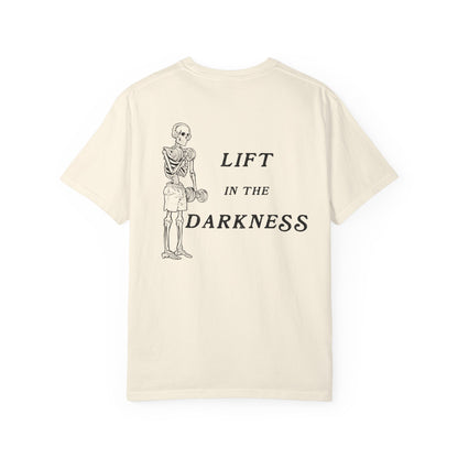 Beige t-shirt with skeleton graphic and text 'Lift in the Darkness' on a white background