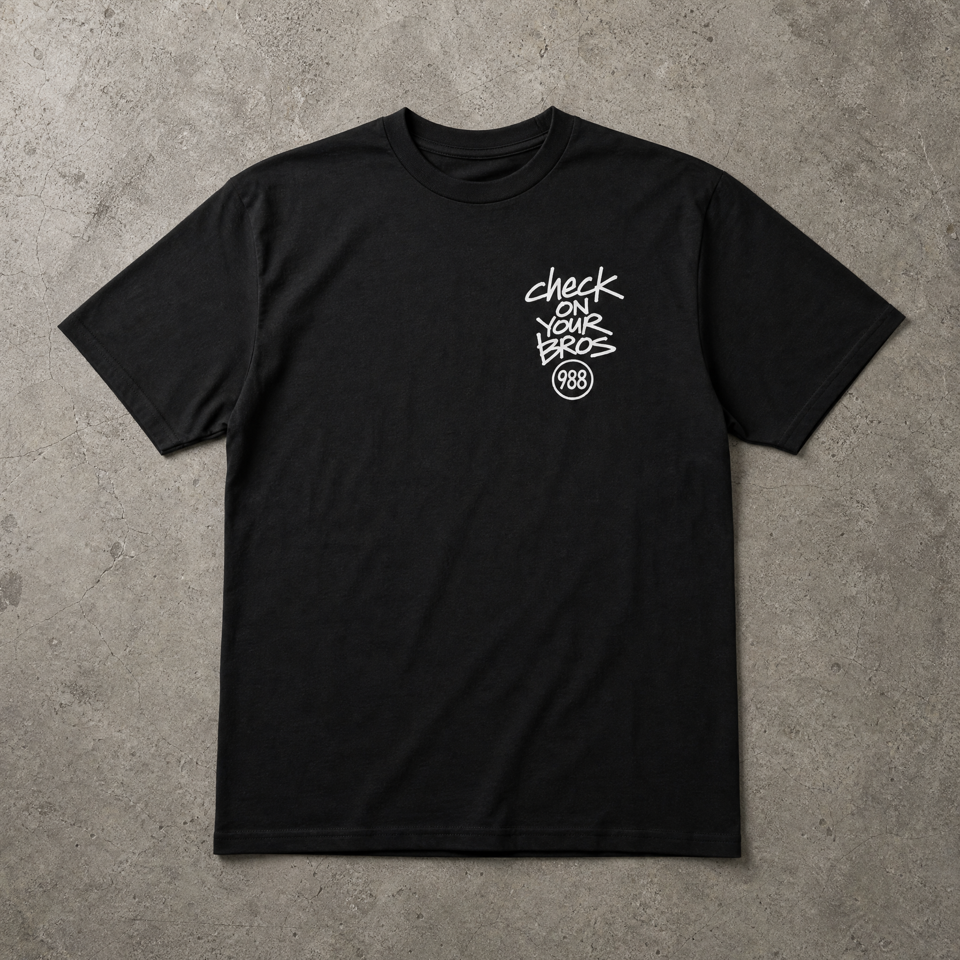 Black t-shirt with white text on a gray concrete surface