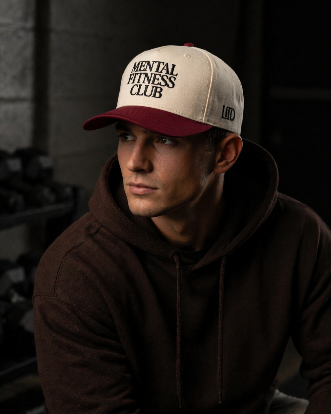 Man wearing a cap with 'Mental Fitness Club' text in a dark setting