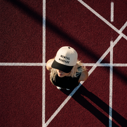 Person wearing a cap with 'Mental Warfare' text on a red patterned floor.