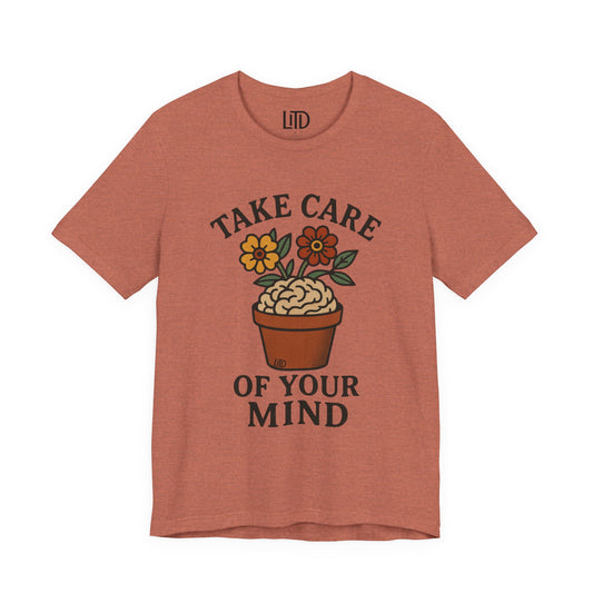 Coral t-shirt with 'Take Care of Your Mind' graphic design on a white background